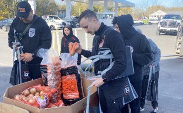 While cars lined up behind them, volunteers rushed to fill bags at Route 54’s annual Harvestfest food give-away. (Photo by Jim C. Powless)