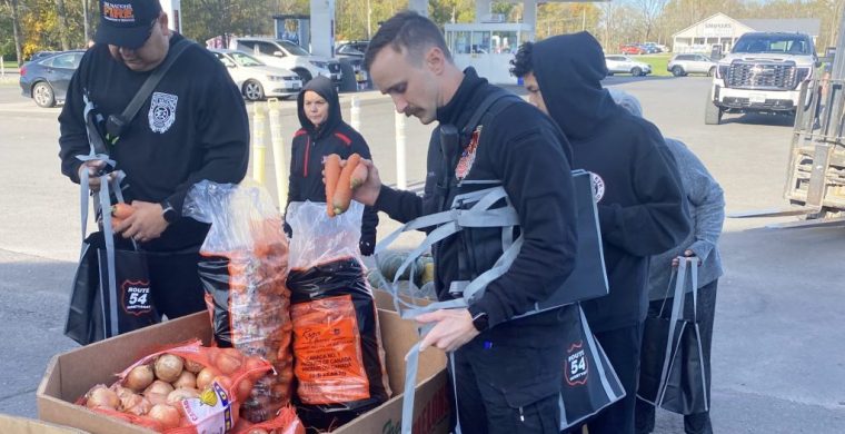 While cars lined up behind them, volunteers rushed to fill bags at Route 54’s annual Harvestfest food give-away. (Photo by Jim C. Powless)