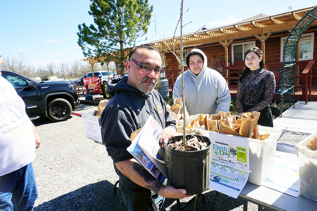 Six Nations residents had a chance to mark Earth Day 2025 with free trees at Turtle Island News’ annual give-away, and with the help of volunteers, Dharma Green and Allie Doxtater, one lucky guy, Doug Henhawk, walked away with a hazelnut tree - one of many fruit trees as well as cedar and white pines given away. (Photo by Jim C. Powless)