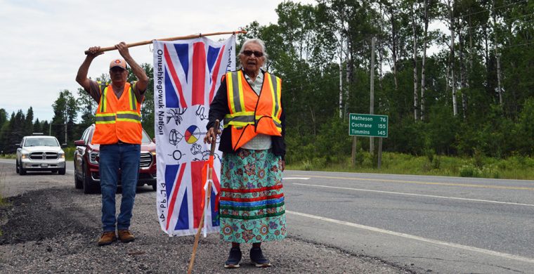 Still strong and dedicated, Elder Angela Ashishkeesh of Attawapiskat First Nation participates in a protest walk against Ontario’s Bill 5 and Canada’s Bill C5. Also seen in the photo is flag bearer Rick Cheechoo, Moose Cree FN.