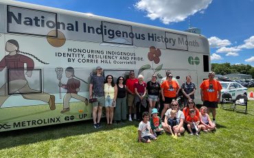 Artist Corrie Hill and her extended family posed in front of the Metrolinx bus featuring her work. (Photo by Alex Murray)